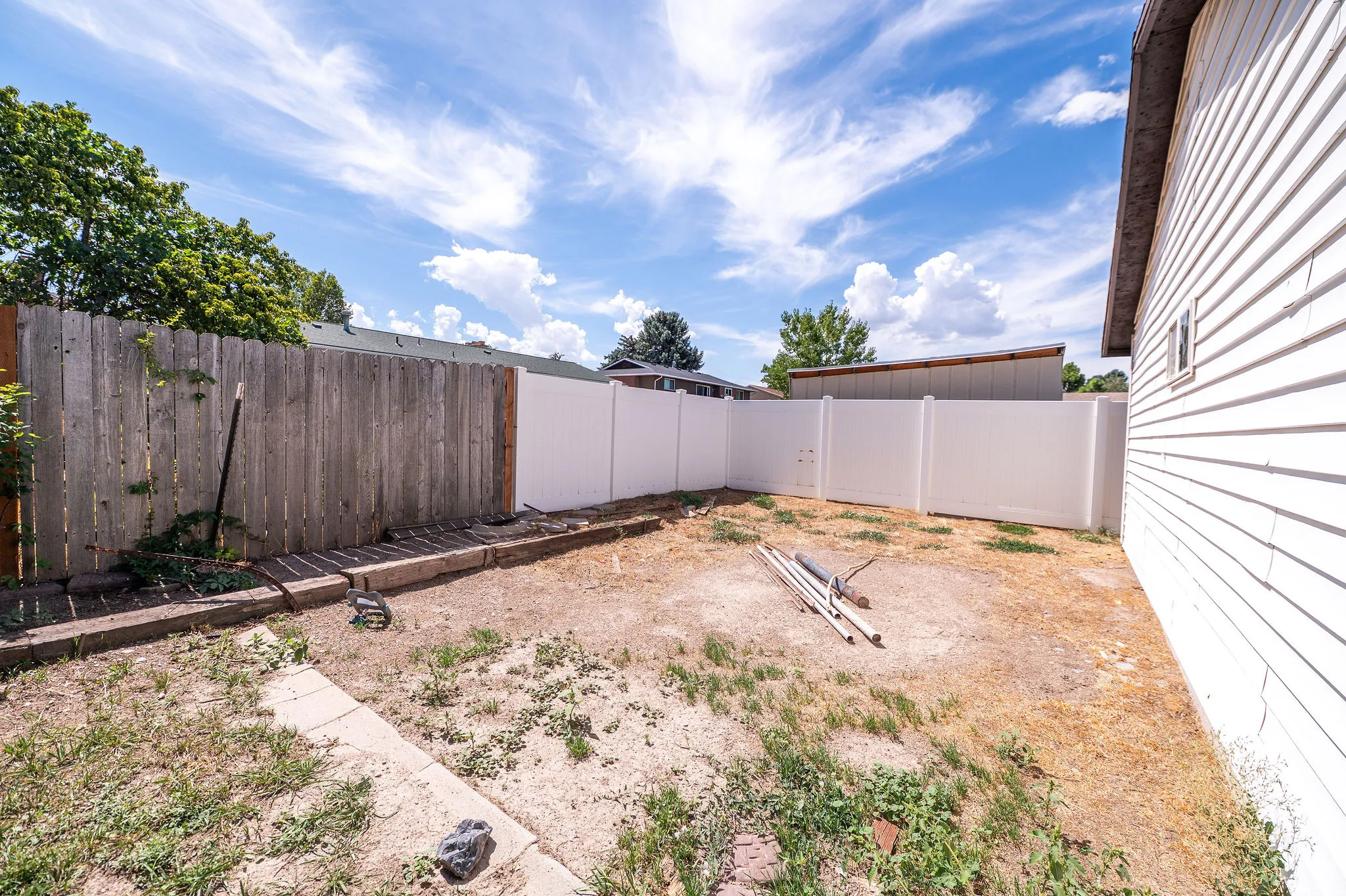 Private backyard space featuring a partial privacy fence and an exterior wall with horizontal siding