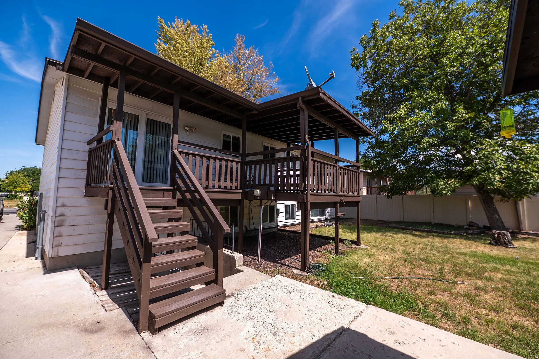 Exterior featuring white siding, a brown outdoor staircase, and a covered deck with brown railings