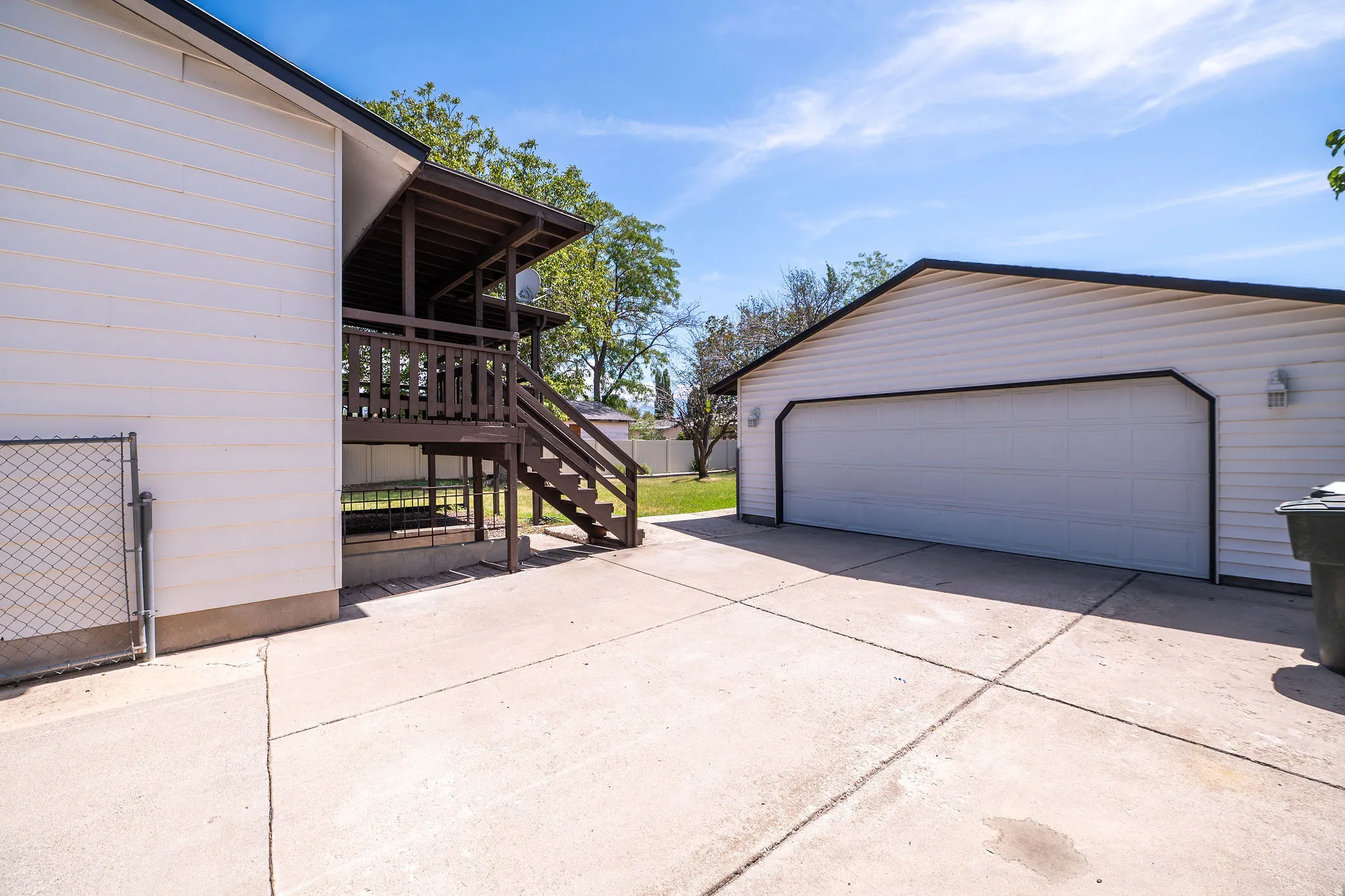 Detached garage with a wide overhead door, exterior wall sconces, and a concrete driveway