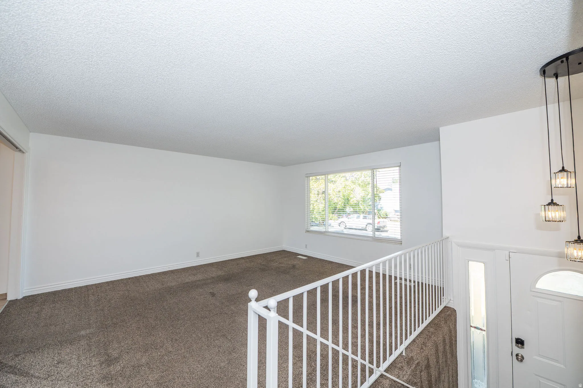 Spacious room featuring neutral carpeting, white walls, and a large window with horizontal blinds