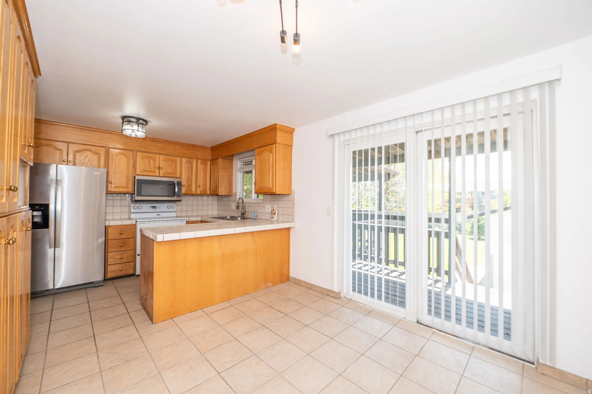 Kitchen featuring wood cabinetry, stainless steel appliances, and a tiled backsplash