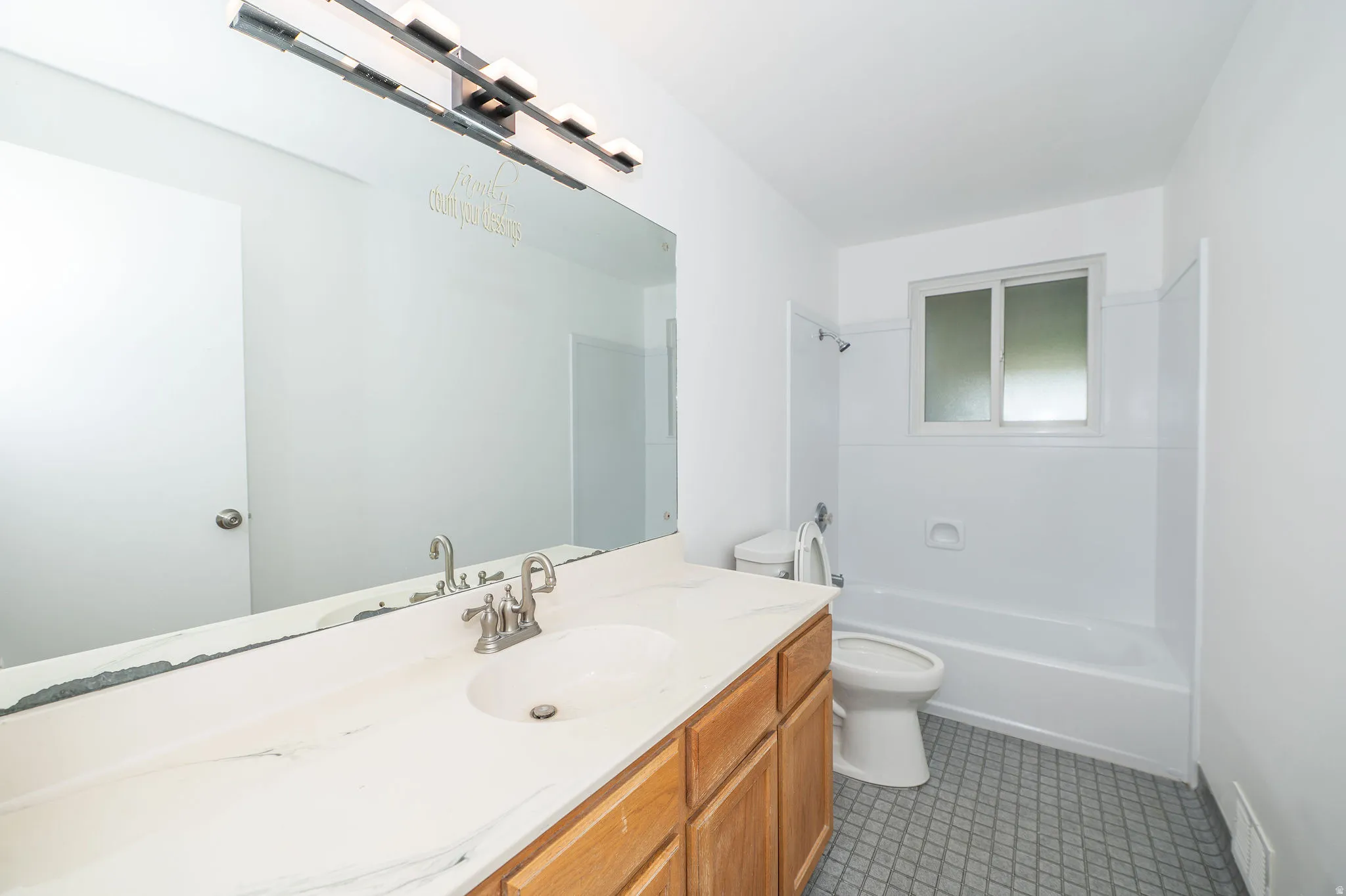 Bathroom vanity with an integrated sink, brushed nickel faucet, and a large wall-mounted mirror
