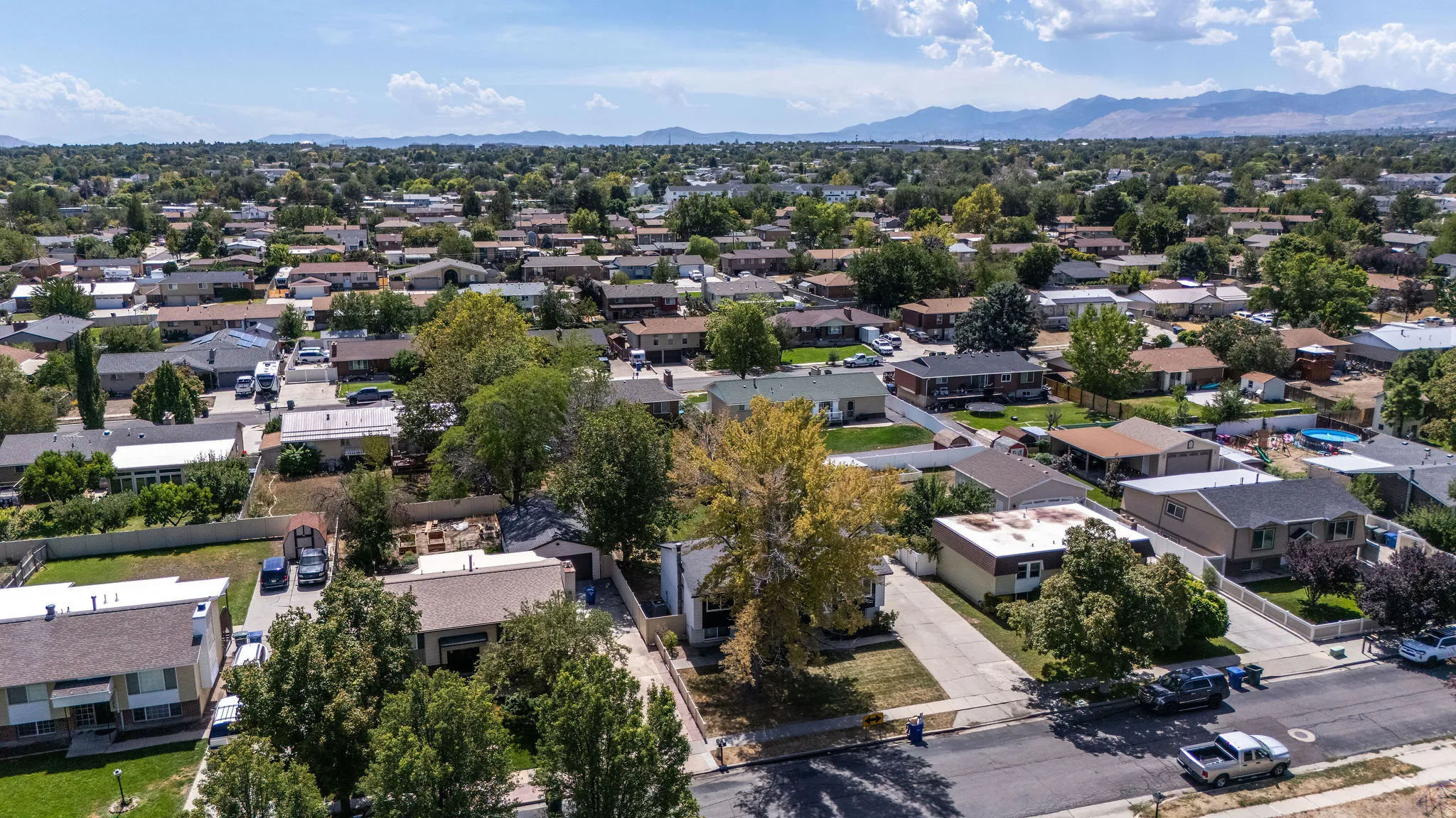 Residential neighborhood with mature trees, established properties, and distant mountain ranges