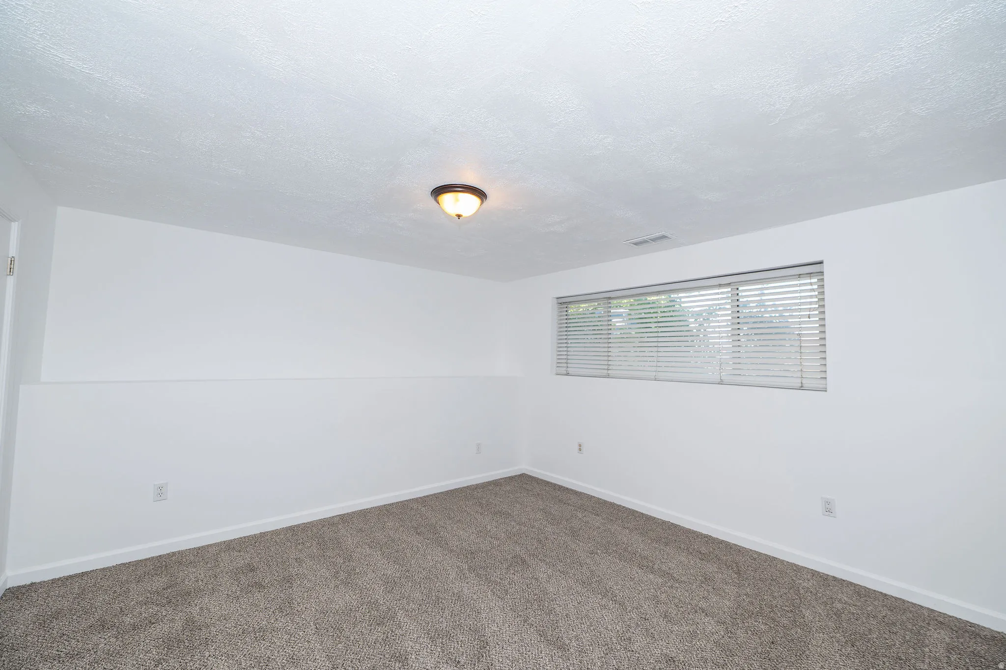Neutral wall color with textured ceiling and wall-to-wall carpeting