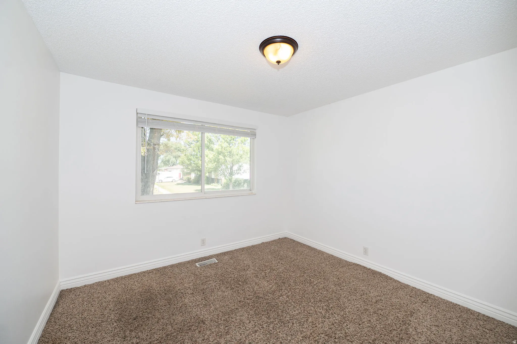 Carpeted flooring, white painted walls, and a window with blinds