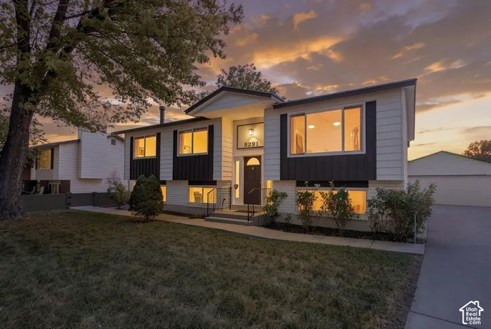 Split-level residence featuring a contrasting façade, prominent front entry with sidelights, and an expansive concrete driveway