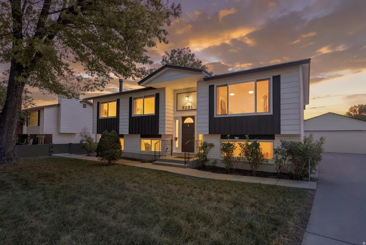 Split-level residence featuring a contrasting façade, prominent front entry with sidelights, and an expansive concrete driveway