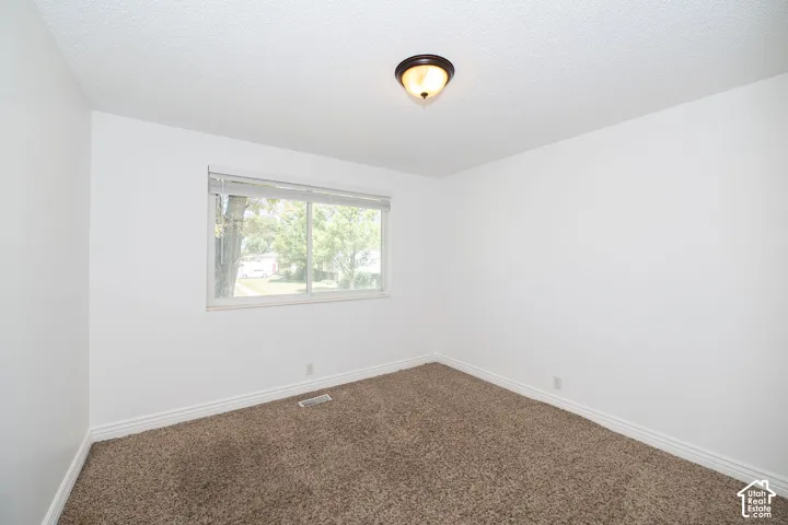 Carpeted flooring, white painted walls, and a window with blinds
