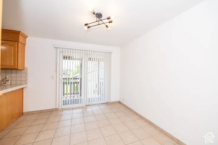 Recessed lighting fixture, light wood cabinetry, tiled backsplash, tile flooring, and sliding glass door