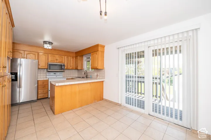 Kitchen featuring wood cabinetry, stainless steel appliances, and a tiled backsplash