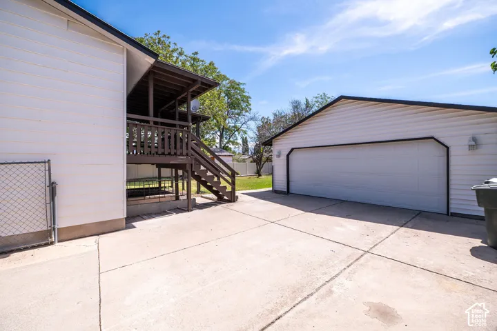 Detached garage with a wide overhead door, exterior wall sconces, and a concrete driveway