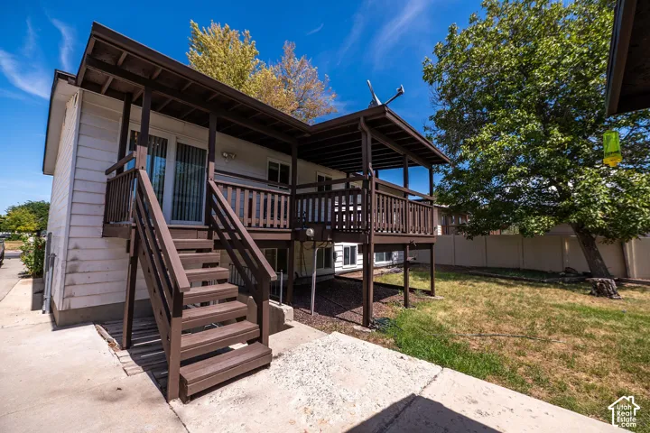 Exterior featuring white siding, a brown outdoor staircase, and a covered deck with brown railings