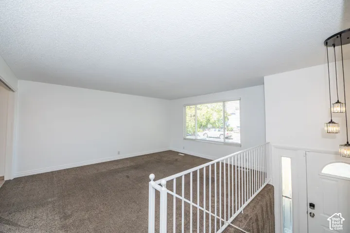 Spacious room featuring neutral carpeting, white walls, and a large window with horizontal blinds
