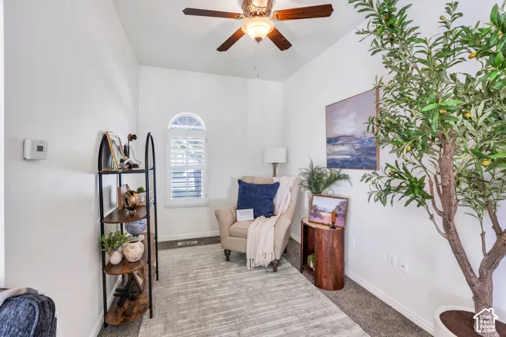 Vaulted ceiling with an attached ceiling fan, arched window with plantation shutters, and light-toned carpet flooring