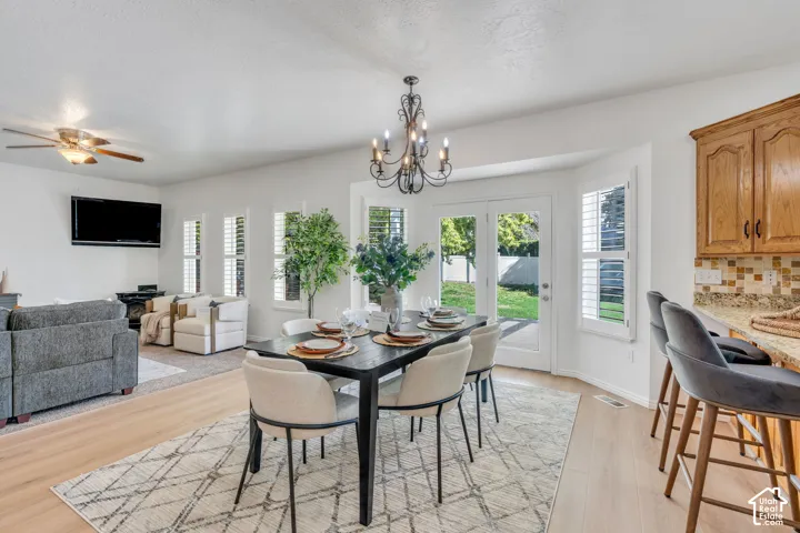 Open-concept living area featuring wood-finish flooring, a contemporary chandelier, and a breakfast bar with stone countertops