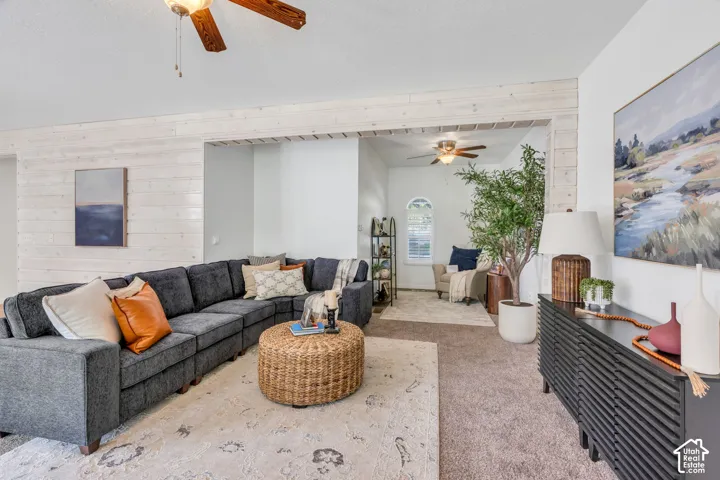 Distressed wood-finish accent wall, ceiling fan with light fixture, recessed opening, arched window, and built-in shelving
