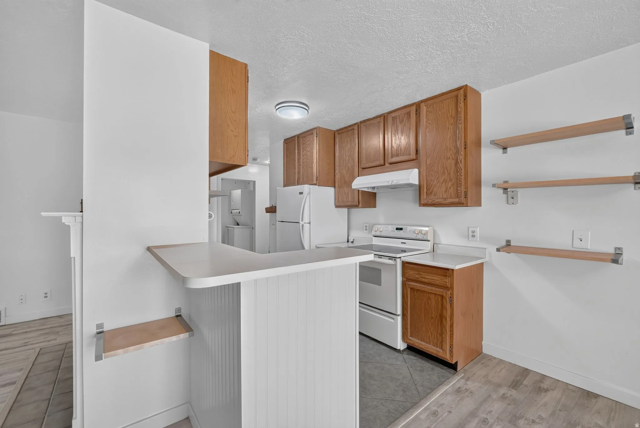 Kitchen featuring wood cabinetry, white appliances, a breakfast bar, and open shelving