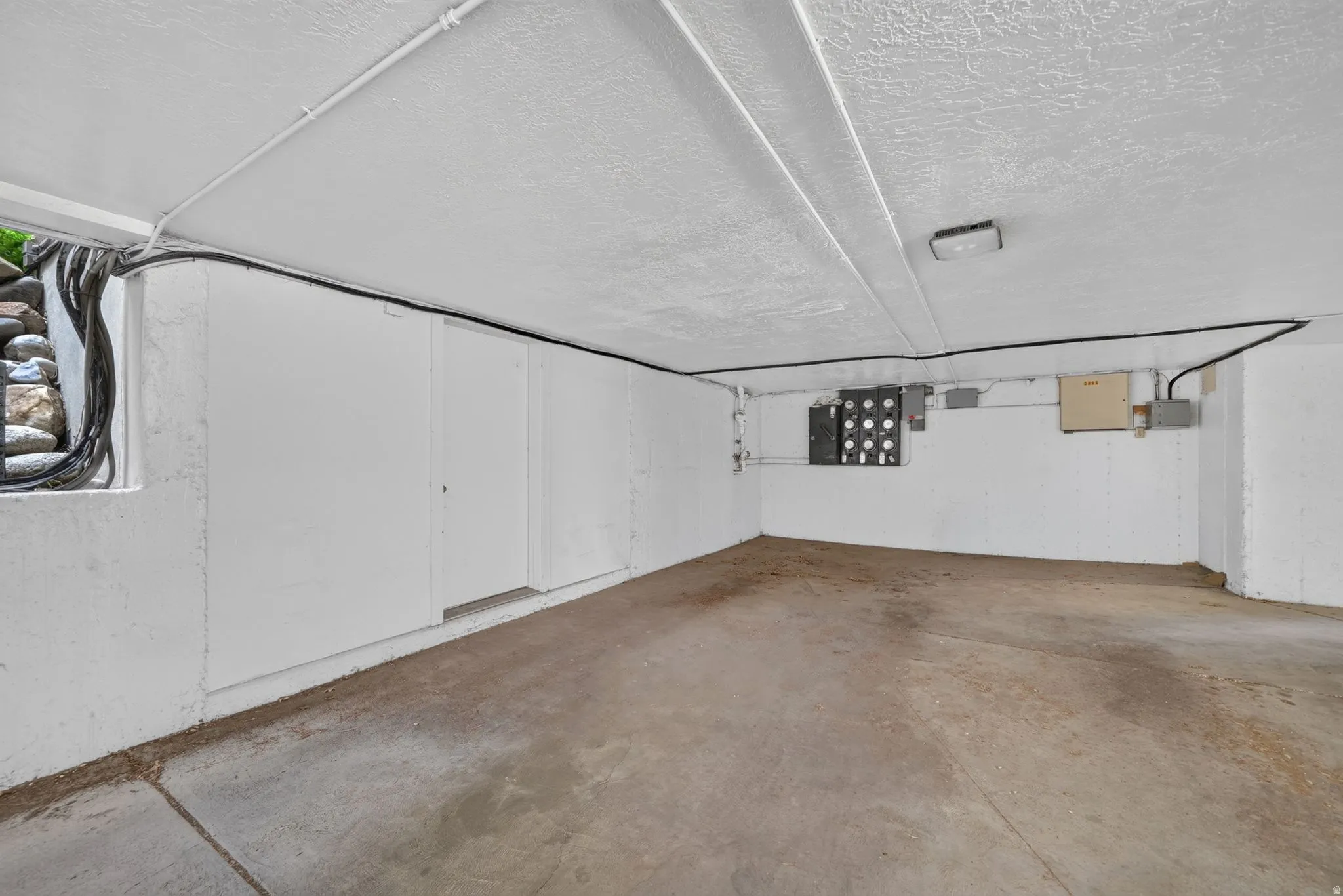 Concrete flooring, textured ceiling, fluorescent lighting, and built-in utility access panels