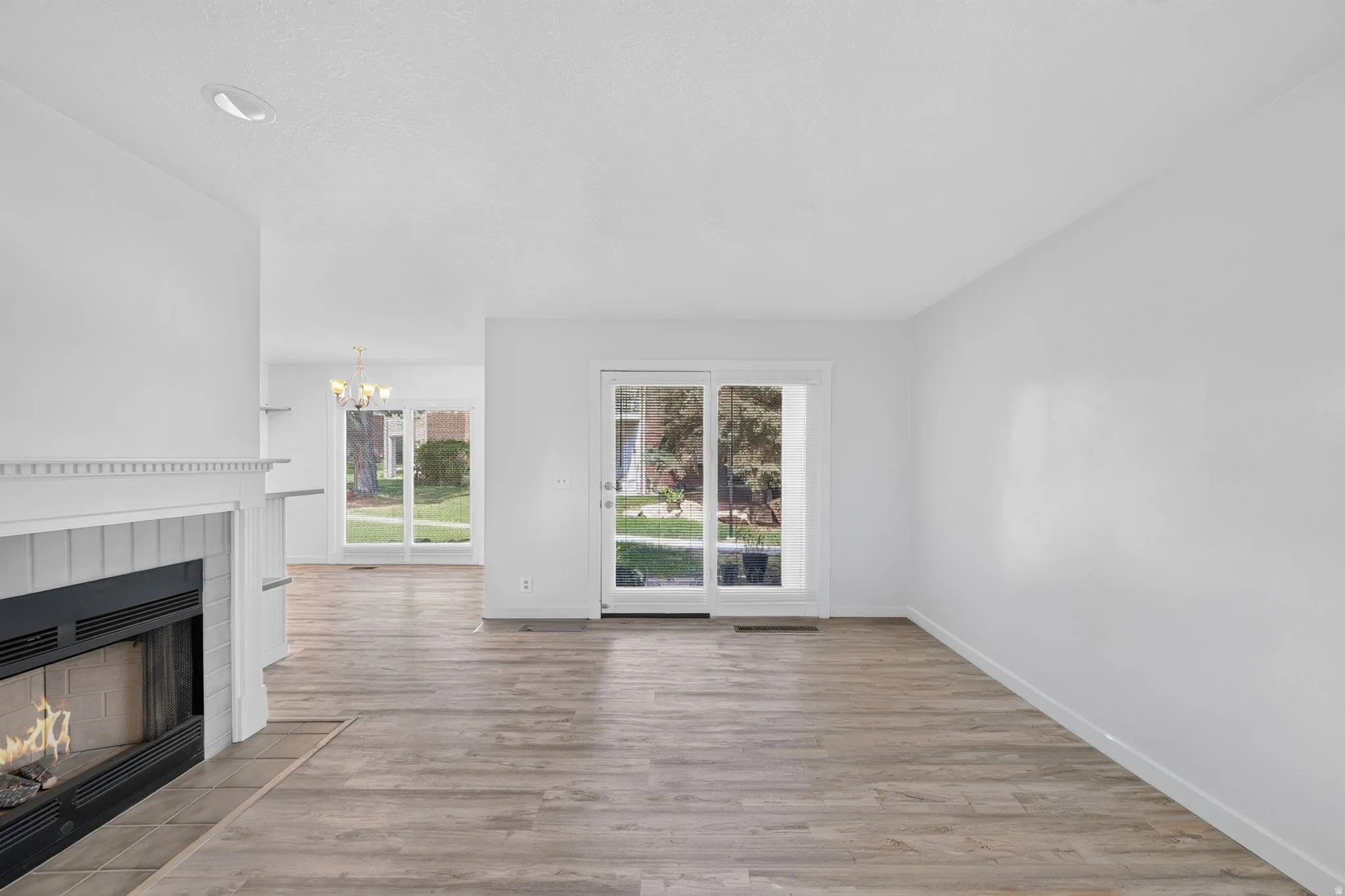 Fireplace with a tile surround, wood-finish flooring, recessed lighting, and a glass sliding door