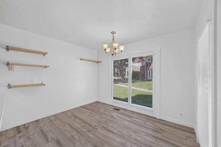 Wood-finish flooring, white walls, built-in shelving, glass sliding door, and a chandelier fixture