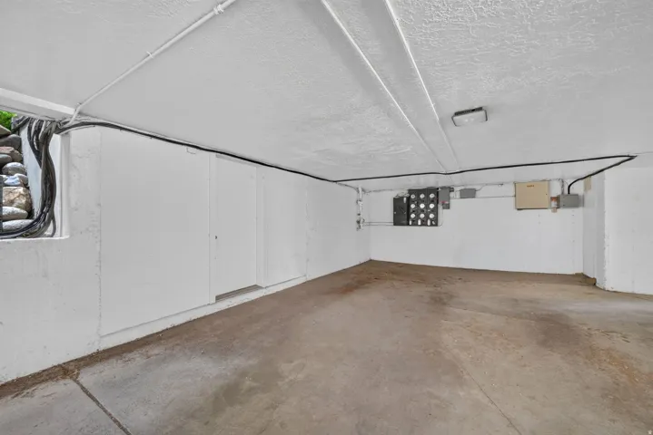Concrete flooring, textured ceiling, fluorescent lighting, and built-in utility access panels