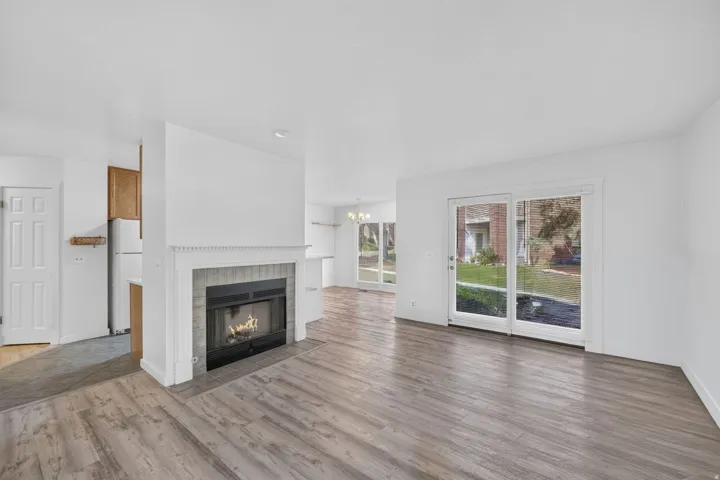 Wood-finish flooring, white walls, and a fireplace with a stone-look surround and mantel