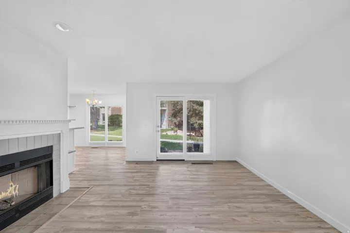 Fireplace with a tile surround, wood-finish flooring, recessed lighting, and a glass sliding door