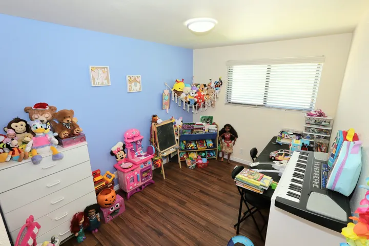 Room featuring wood-finish flooring, a single window with blinds, and a flush-mount ceiling light fixture