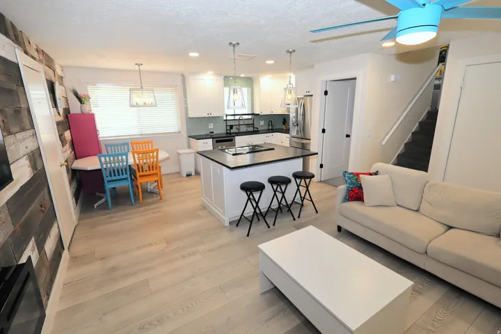 Open-concept living space with wood-finish flooring, a kitchen featuring an island with a built-in cooktop, and white cabinetry
