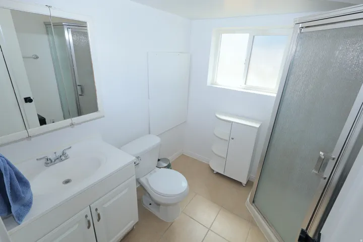 White vanity with integrated sink, chrome faucet, and mirrored medicine cabinet