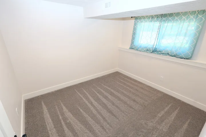 Light-colored walls, patterned gray carpet, and a window with a white sill