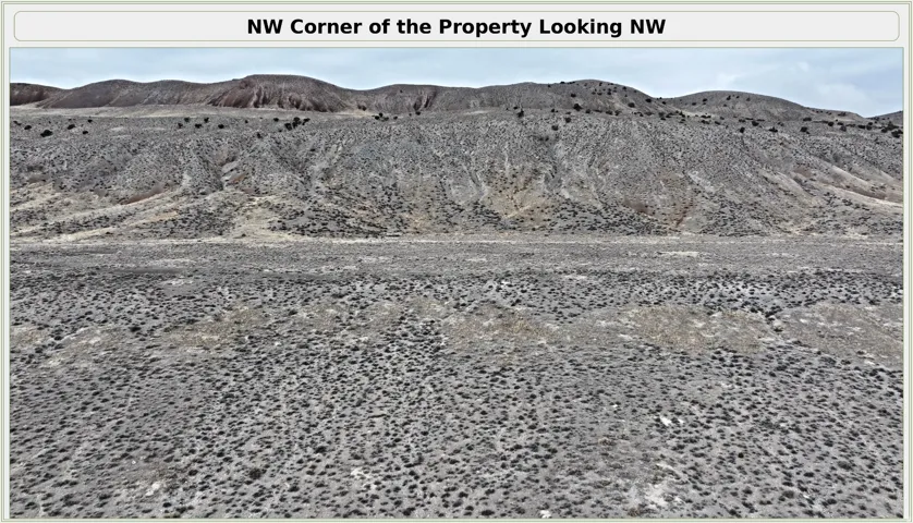 Additional contentThe image shows the NW corner of a raw, undeveloped property with expansive gravel and stone ground coverage, backed by distant mountainous terrain