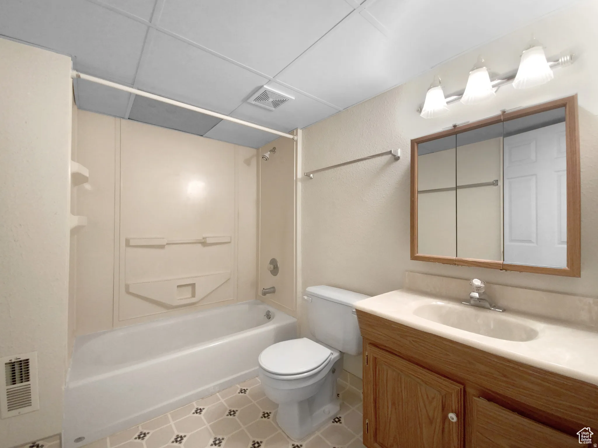 Previous picture Bathroom featuring a built-in bathtub with shower, a wood-finish vanity with an integrated sink, a mirrored medicine cabinet, and a tiled floor