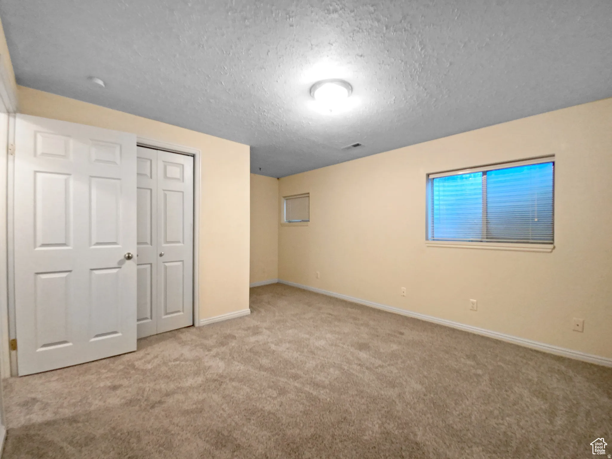 Previous picture Soft carpeting throughout, featuring two windows, a ceiling-mounted light fixture, and two bi-fold closet doors