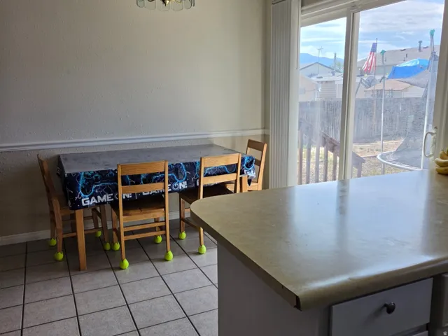 Tile flooring, built-in kitchen island with cabinet storage, sliding glass door, overhead lighting fixture, chair rail molding