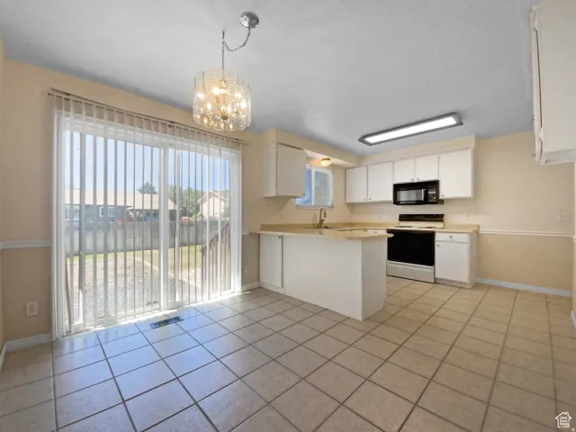 Previous picture Tiled flooring, sliding glass door, white cabinetry, light-toned countertops, and ceiling-mounted lighting fixtures