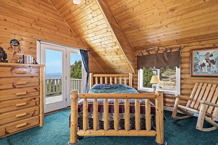 Wood-paneled walls and ceiling, pitched ceiling, and double French doors opening to an outdoor balcony