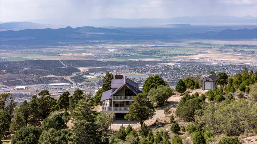 Mountain-side property featuring a multi-level structure with a gabled roof and an exterior balcony