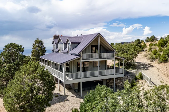 Multi-level residence featuring a metal roof, dormer windows, and a wraparound covered porch