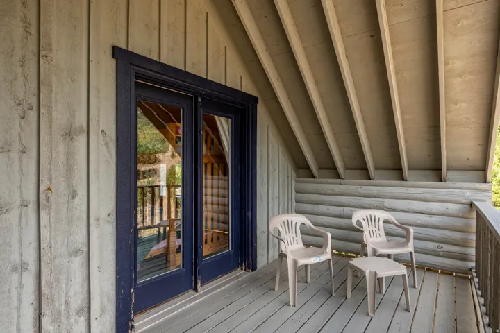 Private balcony with wood-finish decking, exposed beams, and a log-style lower wall