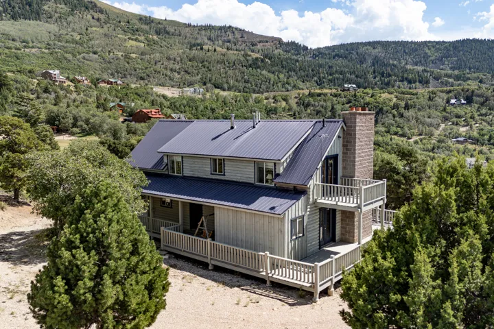 Multi-level dwelling with a metal roof, wood siding, and stone chimney