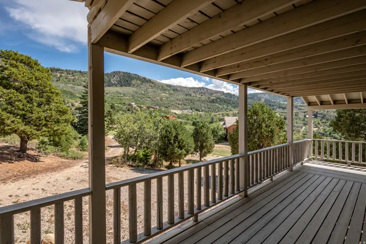 Expansive outdoor deck with wood-finish flooring, sturdy railing, and a slatted ceiling structure
