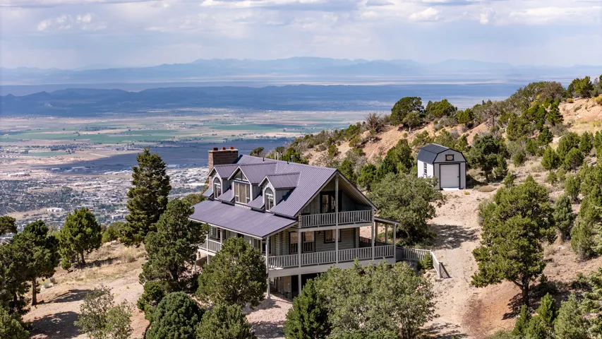 Property featuring a multi-level exterior, an expansive balcony, a metal roof, a prominent chimney, and an additional detached structure
