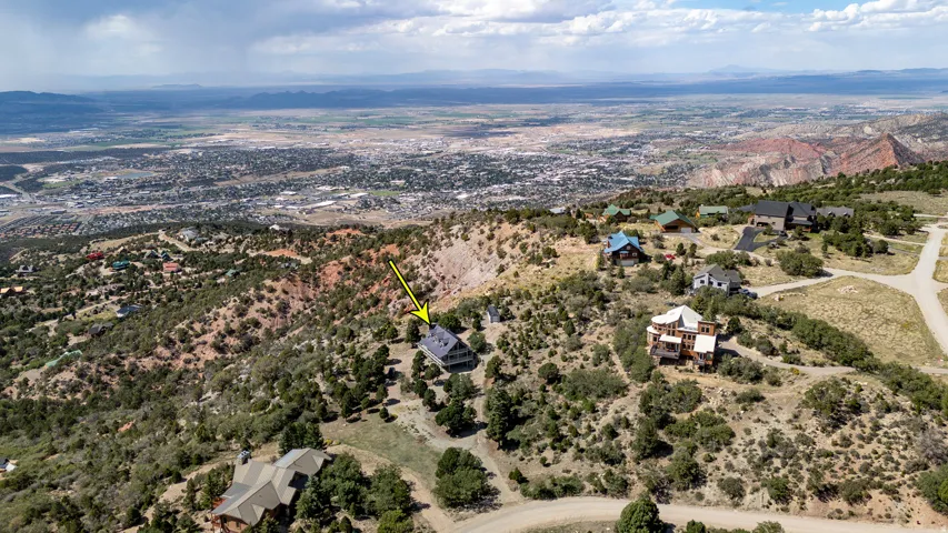 Hillside property with natural landscaping, a pitched roof, and a visible balcony, situated among similar residences