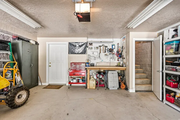 Concrete flooring with built-in workbench, overhead fluorescent lighting, and interior access door