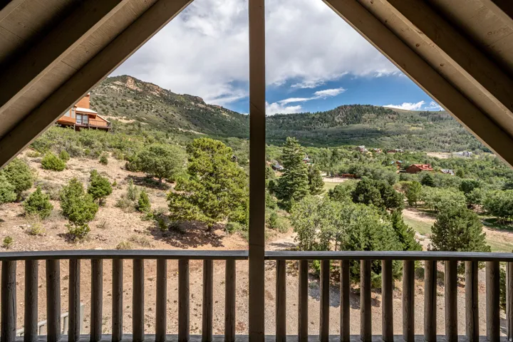 Balcony with wood railing overlooking a mountainous landscape with abundant foliage
