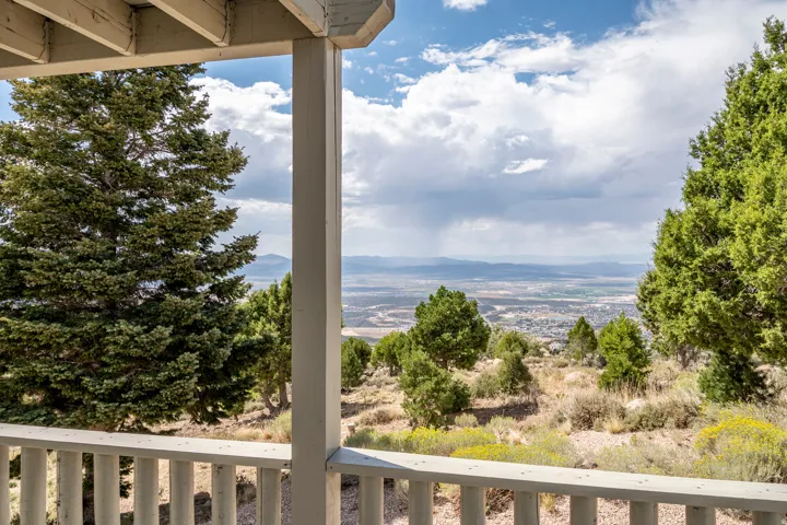 Expansive mountainous scenery and distant cityscape visible from the wooden balcony with classic railings
