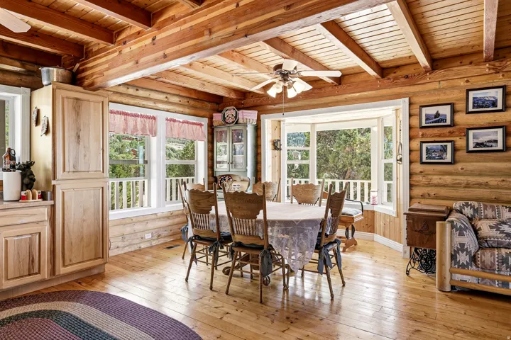 Exposed wood log walls, wood-finish flooring, wood plank ceiling, built-in wood cabinetry, and a bay window