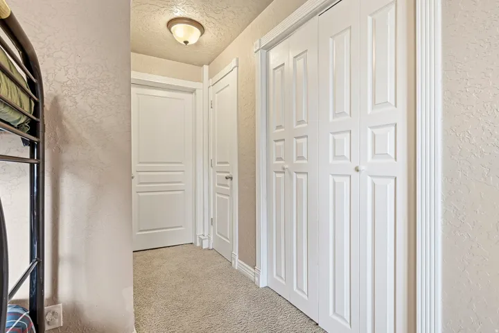 Textured wall finish, recessed ceiling light, white paneled doors, carpet flooring, decorative trim