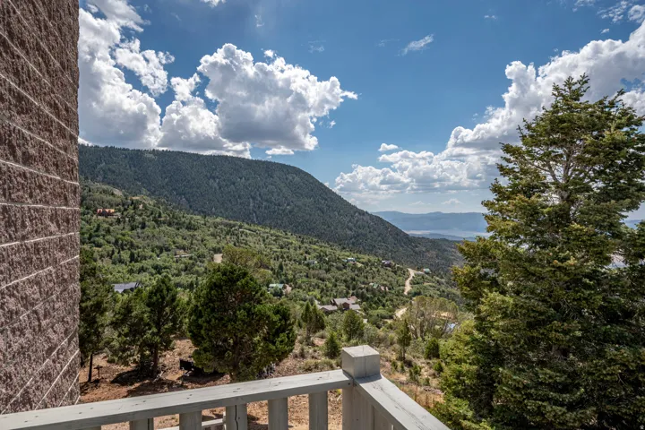 Mountain scenery with distant water, complemented by a balcony with a wooden railing and a textured exterior wall